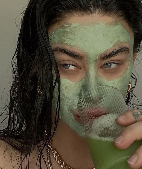 Green face mask on an model drinking green juice